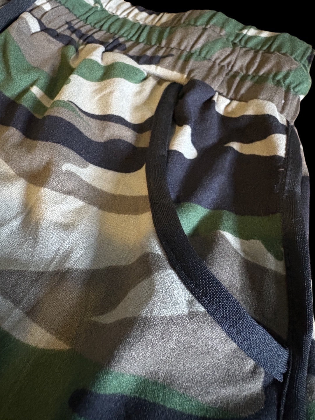 Leaf women's camo training shorts with elastic waistband, drawstring, and black piping trim on a curved hem.