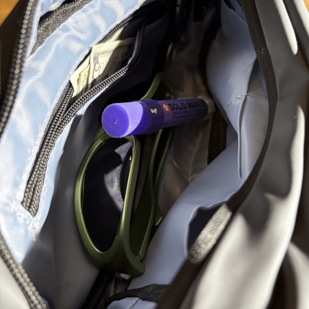Interior view of a Leaf Everyday Wearable Waist Pack showing light blue lining with sunglasses and a marker pen